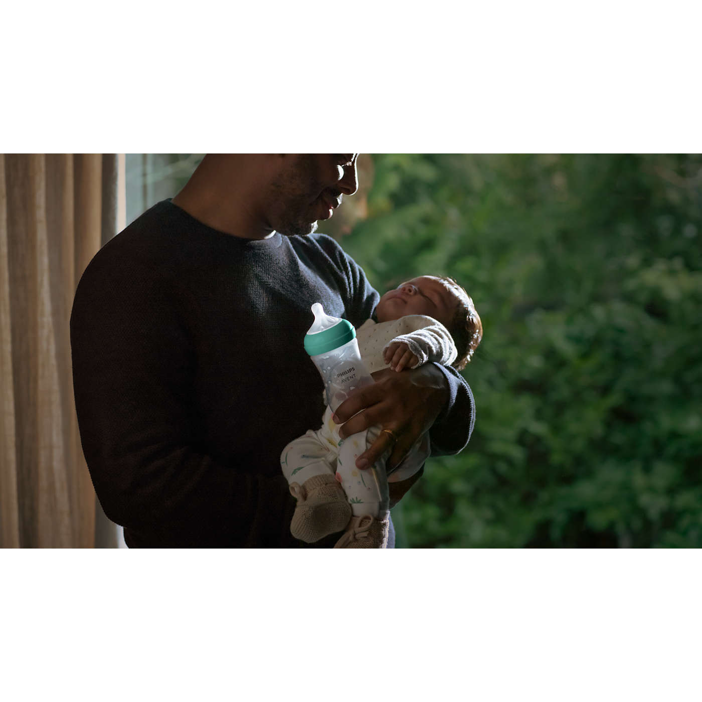 Person holding a baby with a bottle, blurred background