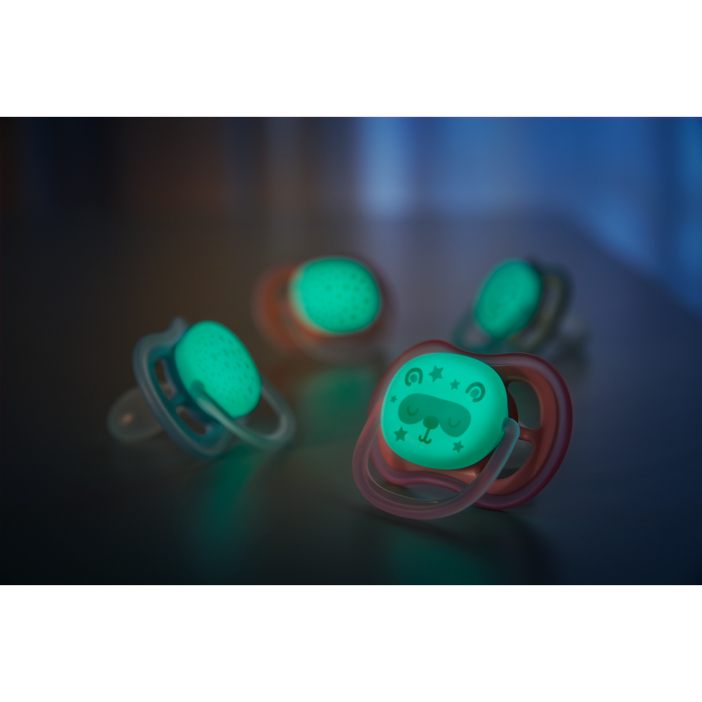 Glowing baby pacifiers on a dark surface