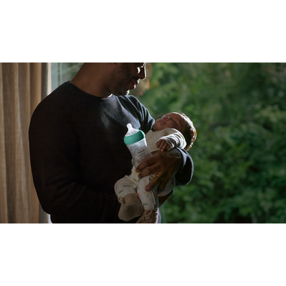 Person holding a baby with a bottle, blurred background