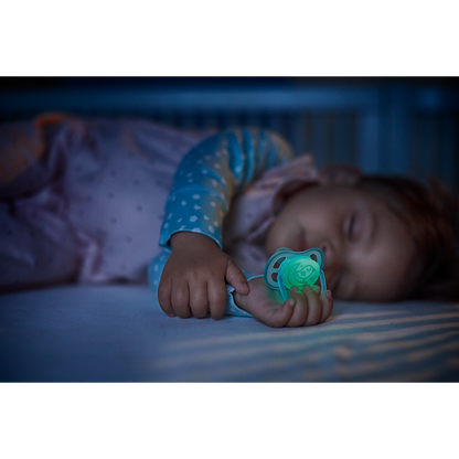 Baby sleeping in a crib with a green pacifier