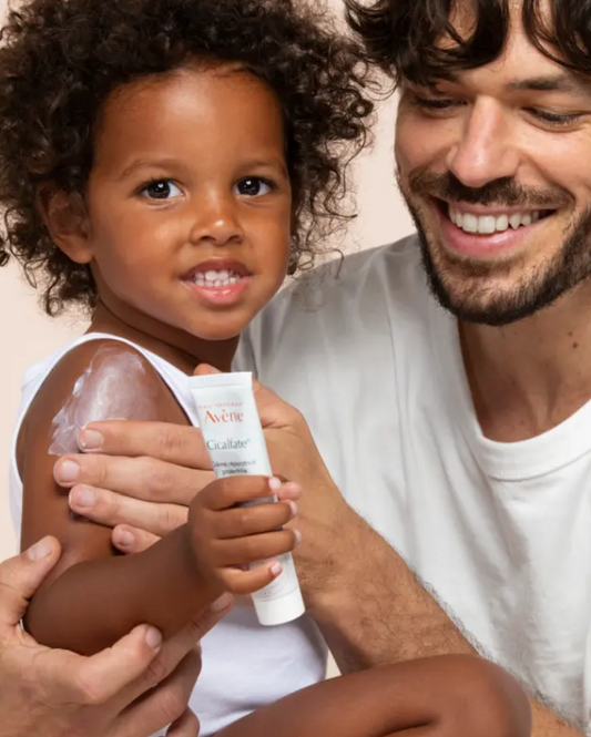 Child holding a tube of Aveeno lotion with a smiling adult