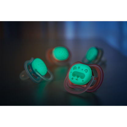 Glowing baby pacifiers on a dark surface